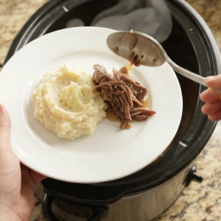 Fork-tender beef roast with shallots and carrots in a slow cooker, glistening with butter sauce.