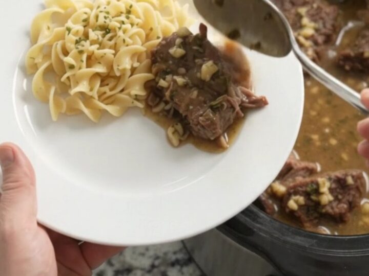 Slow-cooker beef roast with mushrooms and gravy in a black crockpot