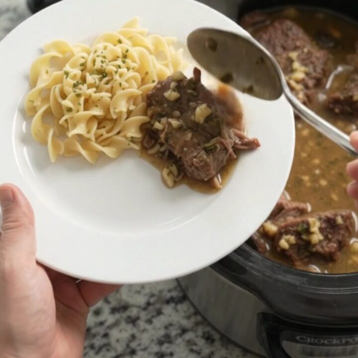 Slow-cooker beef roast with mushrooms and gravy in a black crockpot
