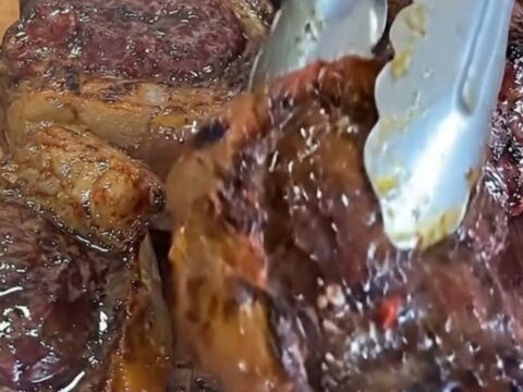 A wooden board holding perfectly seared, juicy steak bites with a golden garlic butter glaze.