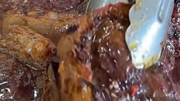 A wooden board holding perfectly seared, juicy steak bites with a golden garlic butter glaze.