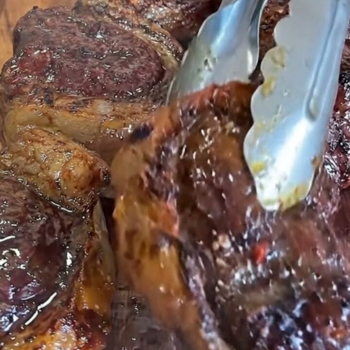 A wooden board holding perfectly seared, juicy steak bites with a golden garlic butter glaze.