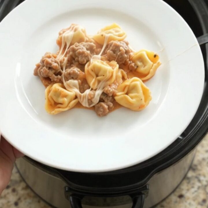 Slow cooker tortellini with sausage, marinara, and melted mozzarella, served in a bowl.