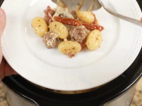 Crockpot Tuscan Sausage Gnocchi with creamy sauce and melted mozzarella, served directly from the slow cooker
