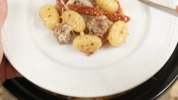 Crockpot Tuscan Sausage Gnocchi with creamy sauce and melted mozzarella, served directly from the slow cooker
