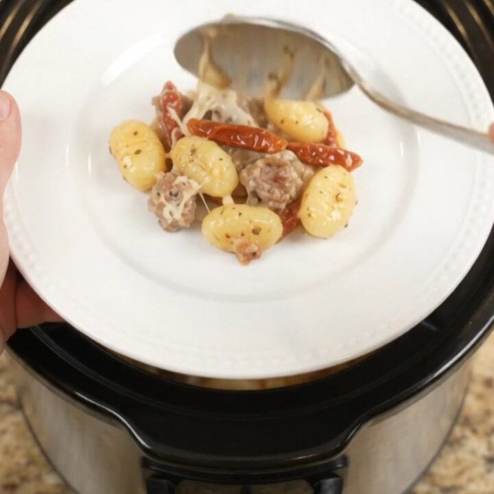 Crockpot Tuscan Sausage Gnocchi with creamy sauce and melted mozzarella, served directly from the slow cooker
