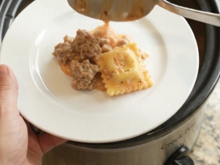Slow cooker filled with bubbling sausage vodka ravioli topped with melted Italian cheeses
