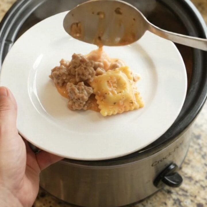 Slow cooker filled with bubbling sausage vodka ravioli topped with melted Italian cheeses
