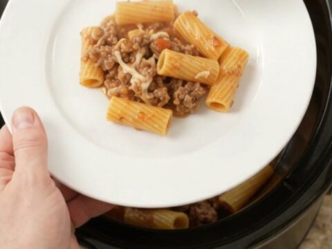 Slow cooker rigatoni with sausage and melted cheese, bubbling in the crockpot