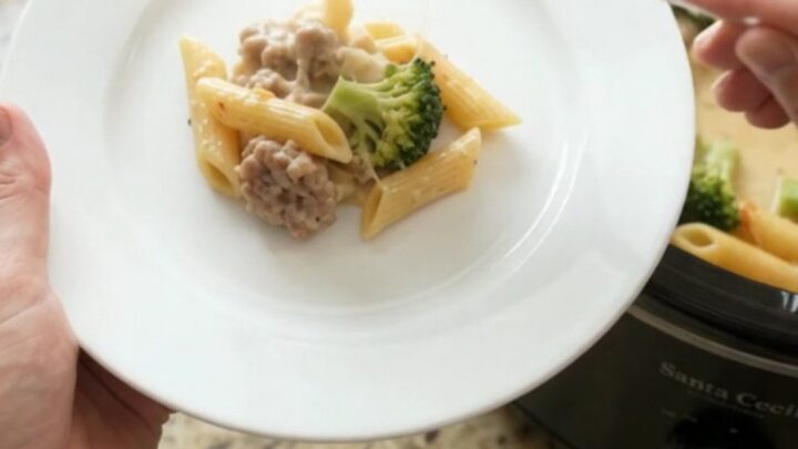 Bubbling slow cooker Parmesan sausage Alfredo penne with melted cheese and steam rising