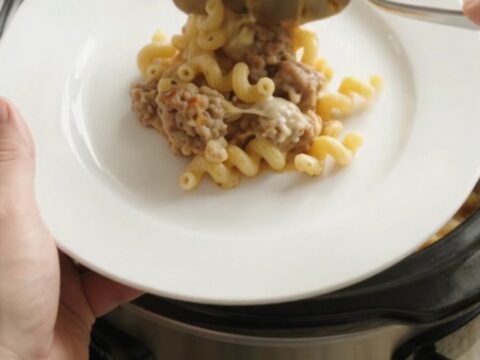 Creamy slow cooker cavatappi with sausage and melted cheese, bubbling in the crockpot.