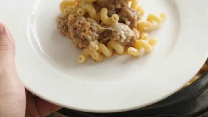 Creamy slow cooker cavatappi with sausage and melted cheese, bubbling in the crockpot.