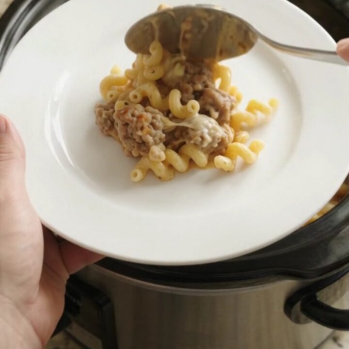 Creamy slow cooker cavatappi with sausage and melted cheese, bubbling in the crockpot.