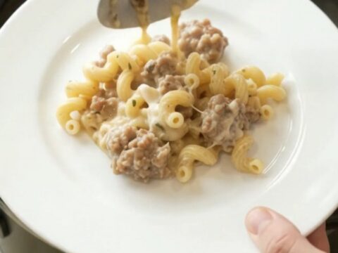 Creamy Crockpot sausage cavatappi with melted provolone and ricotta, served in a black slow cooker.
