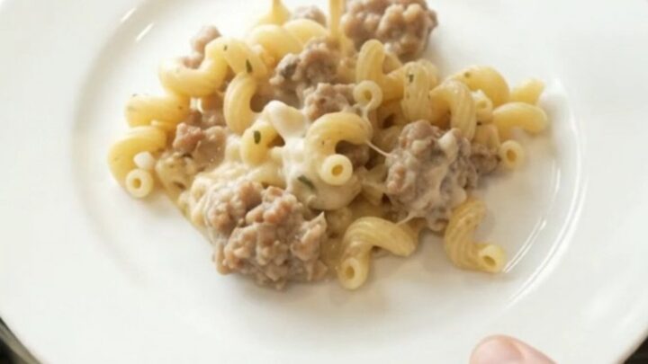 Creamy Crockpot sausage cavatappi with melted provolone and ricotta, served in a black slow cooker.