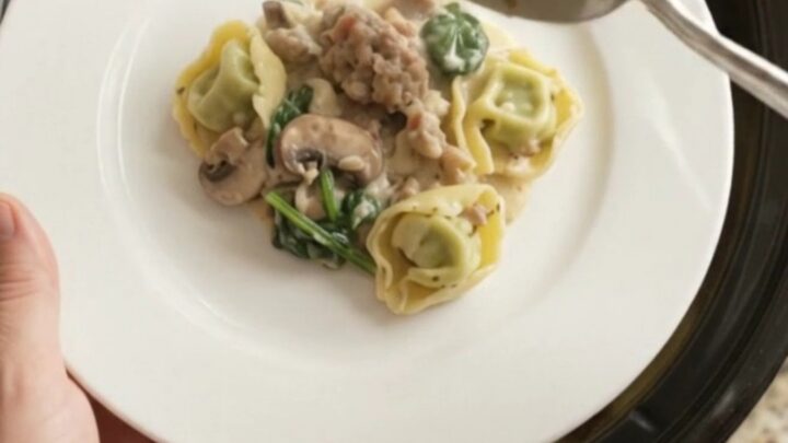 Creamy Crockpot Boursin sausage tortellini with melted cheese and mushrooms, served in a black slow cooker