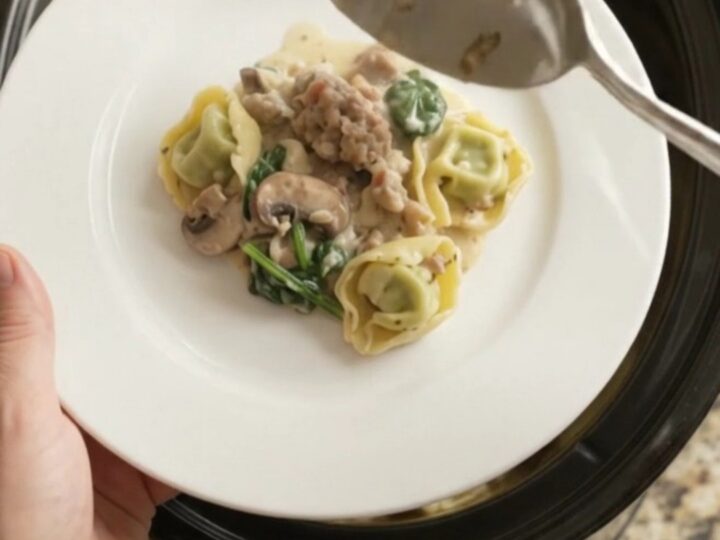 Creamy Crockpot Boursin sausage tortellini with melted cheese and mushrooms, served in a black slow cooker