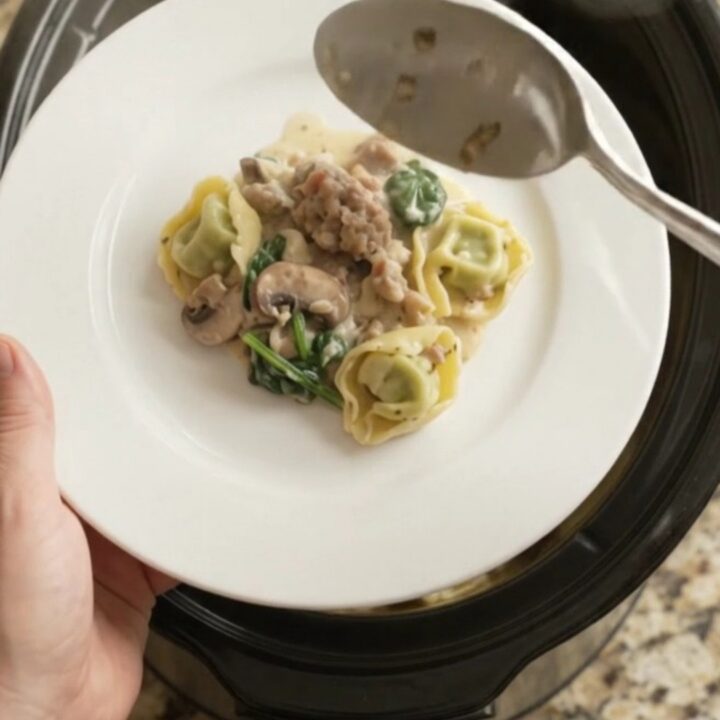 Creamy Crockpot Boursin sausage tortellini with melted cheese and mushrooms, served in a black slow cooker