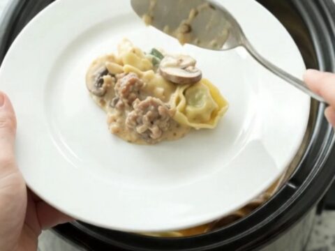 Crockpot Parmesan Sausage Spinach Tortellini in a slow cooker, bubbling with melted cheese