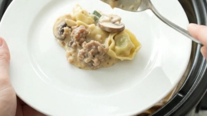 Crockpot Parmesan Sausage Spinach Tortellini in a slow cooker, bubbling with melted cheese