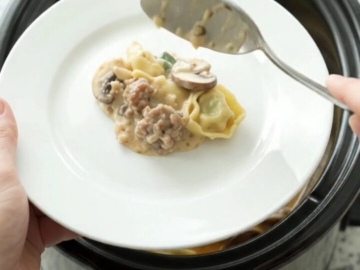 Crockpot Parmesan Sausage Spinach Tortellini in a slow cooker, bubbling with melted cheese