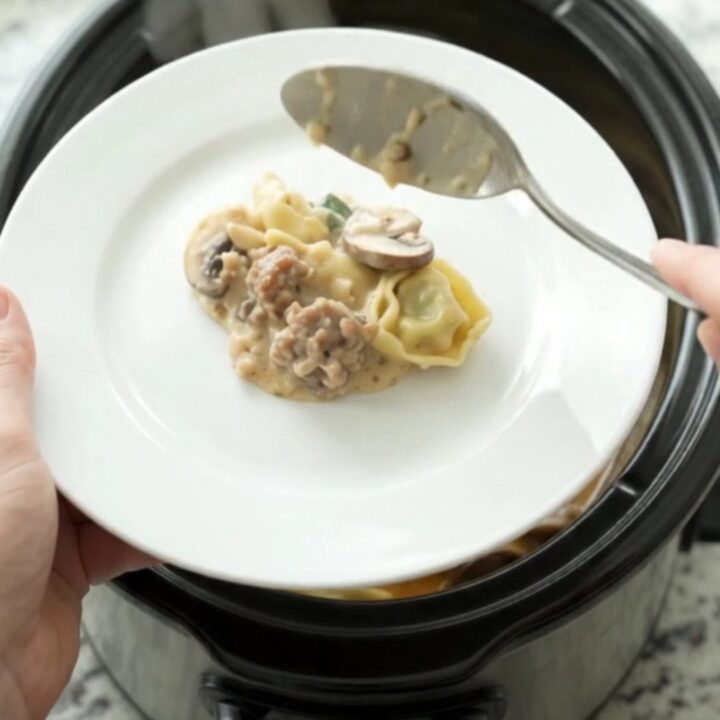 Crockpot Parmesan Sausage Spinach Tortellini in a slow cooker, bubbling with melted cheese