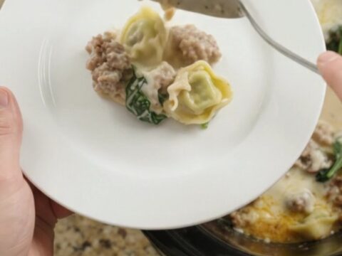 Creamy slow cooker tortellini with sausage and mushrooms in a black crockpot