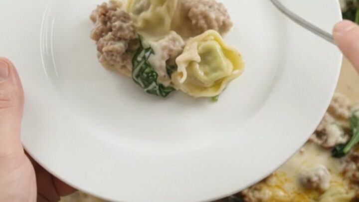 Creamy slow cooker tortellini with sausage and mushrooms in a black crockpot
