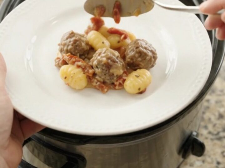 Bubbling slow cooker filled with meatballs, gnocchi, and melted provolone cheese