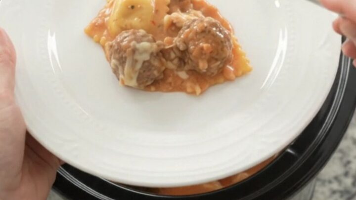 Bubbling Crockpot with meatballs and ravioli in creamy pink vodka sauce topped with melted mozzarella