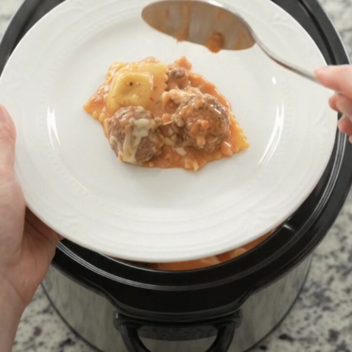 Bubbling Crockpot with meatballs and ravioli in creamy pink vodka sauce topped with melted mozzarella