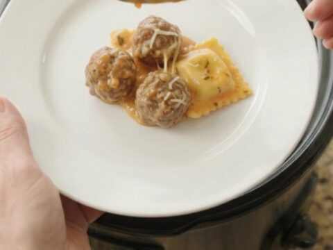 Bubbling slow cooker with meatballs, ravioli, and melted cheese