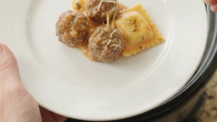 Bubbling slow cooker with meatballs, ravioli, and melted cheese