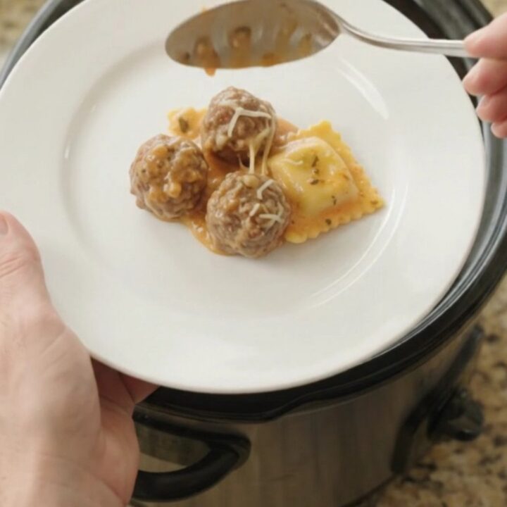 Bubbling slow cooker with meatballs, ravioli, and melted cheese