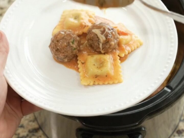 Slow cooker filled with creamy pasta and meatballs in pink vodka sauce, topped with melted fontina