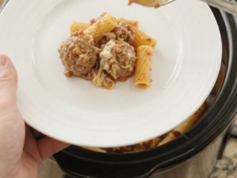 Crockpot Provolone Meatball Bolognese Rigatoni bubbling in the slow cooker with melted cheese and meatballs.