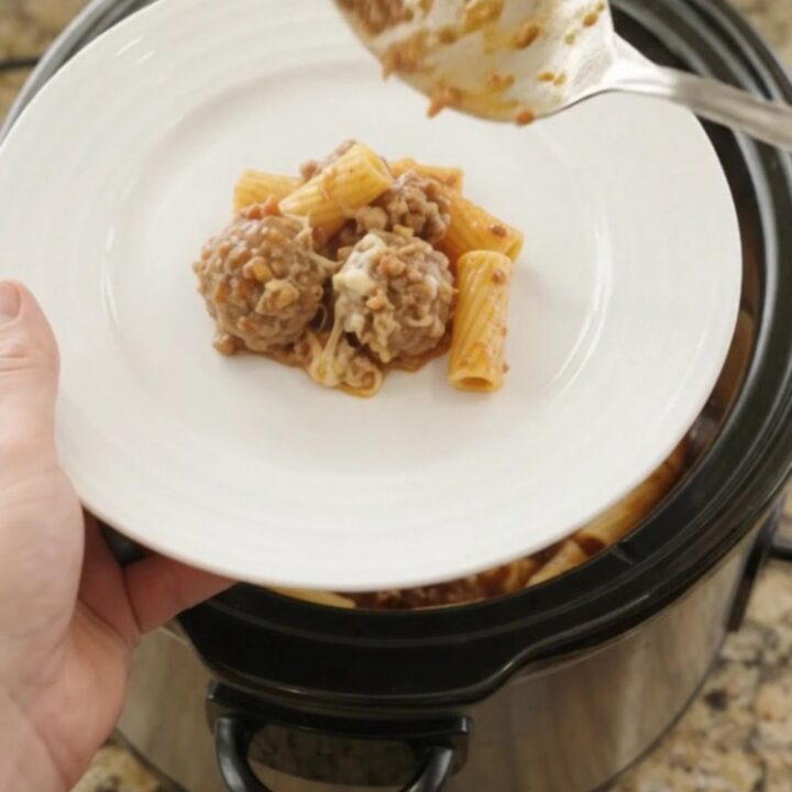 Crockpot Provolone Meatball Bolognese Rigatoni bubbling in the slow cooker with melted cheese and meatballs.