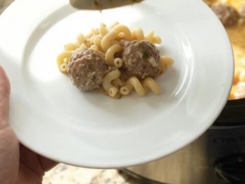 Slow cooker filled with creamy meatball pasta, topped with melted mozzarella