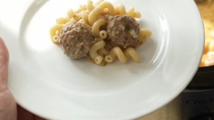 Slow cooker filled with creamy meatball pasta, topped with melted mozzarella