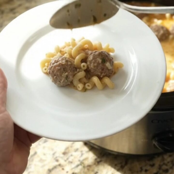 Slow cooker filled with creamy meatball pasta, topped with melted mozzarella