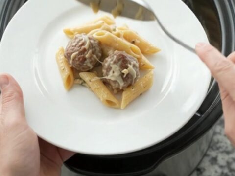 Crockpot Provolone Meatball Alfredo Penne in a slow cooker, bubbling with melted cheese and creamy sauce.
