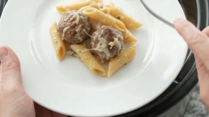 Crockpot Provolone Meatball Alfredo Penne in a slow cooker, bubbling with melted cheese and creamy sauce.