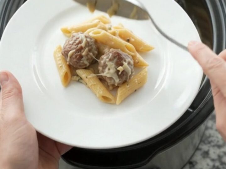 Crockpot Provolone Meatball Alfredo Penne in a slow cooker, bubbling with melted cheese and creamy sauce.