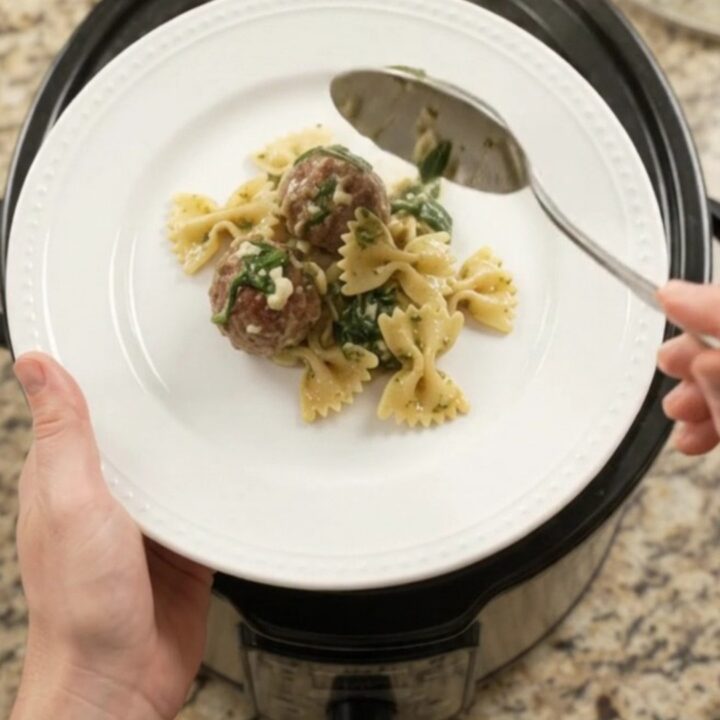 Bubbling Crockpot filled with meatballs, farfalle, spinach, and melted provolone cheese