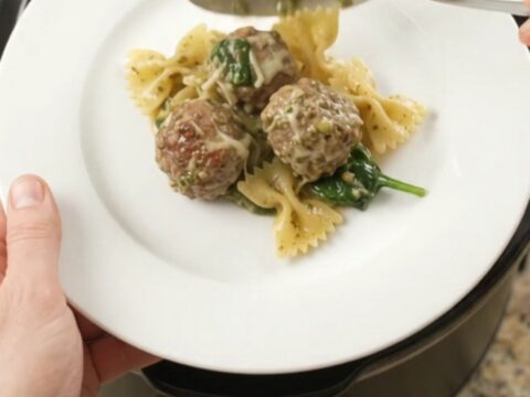 Slow cooker filled with creamy pasta, meatballs, and melted cheese