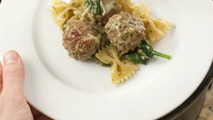 Slow cooker filled with creamy pasta, meatballs, and melted cheese