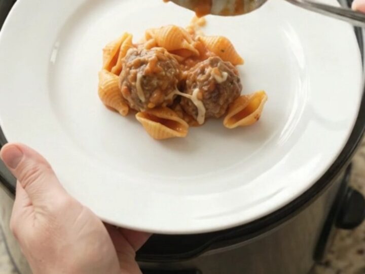 Slow cooker full of creamy meatball pasta shells with melted cheese