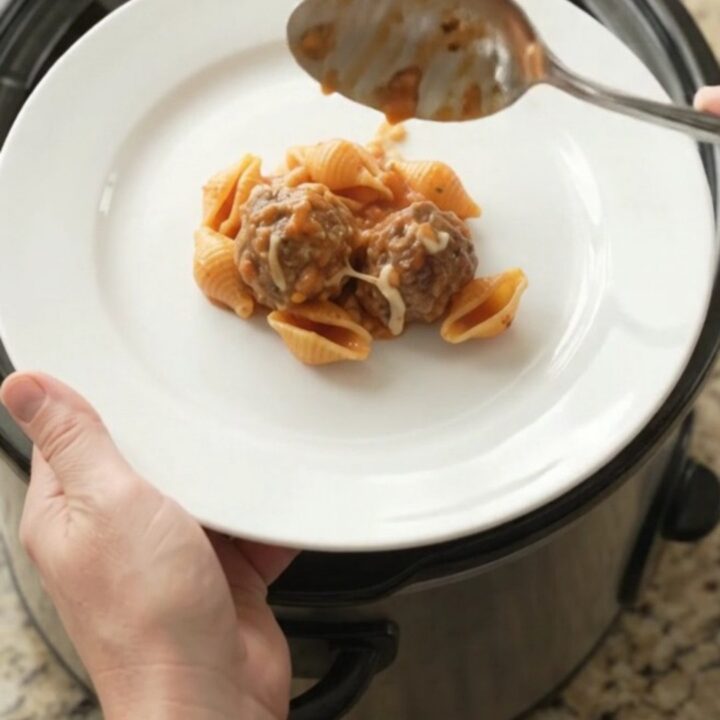 Slow cooker full of creamy meatball pasta shells with melted cheese