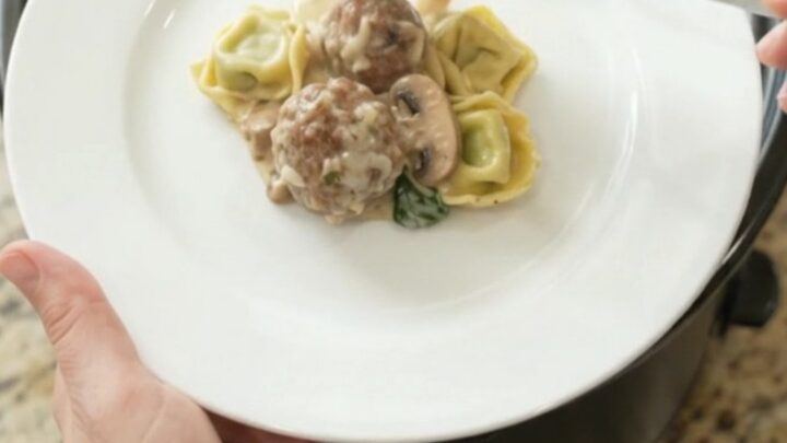 Slow cooker filled with cheesy meatball tortellini, bubbling with melted mozzarella and cream cheese sauce.