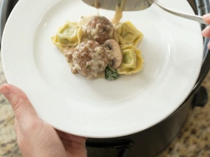 Slow cooker filled with cheesy meatball tortellini, bubbling with melted mozzarella and cream cheese sauce.